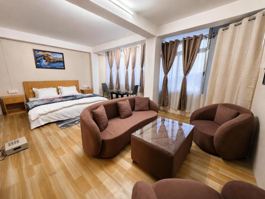 a bedroom with a bed and a couch and chairs at Ananda Homestay in Tawang