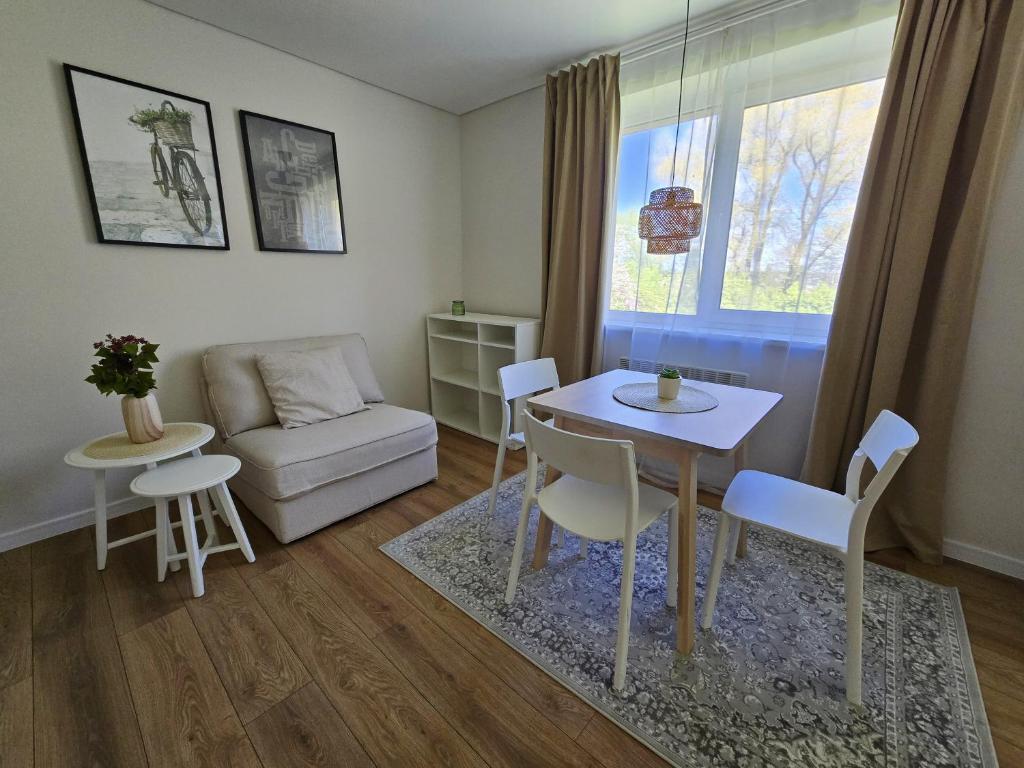 a living room with a table and chairs and a couch at Vilimiškės Apartamentai in Palanga