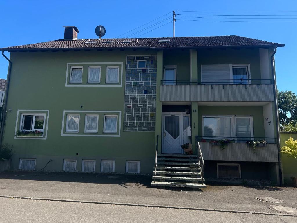 a green house with a porch and stairs on it at Pension Zimmermann in Unteruhldingen