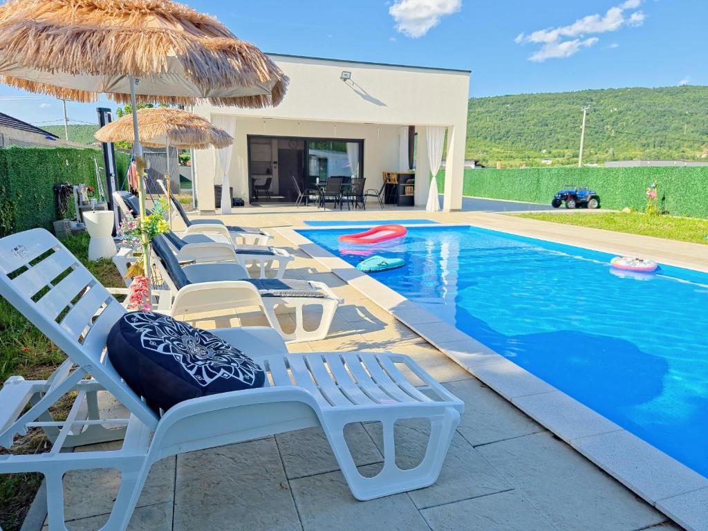 a pool with chairs and umbrellas next to a house at Villa Lea in Bihać