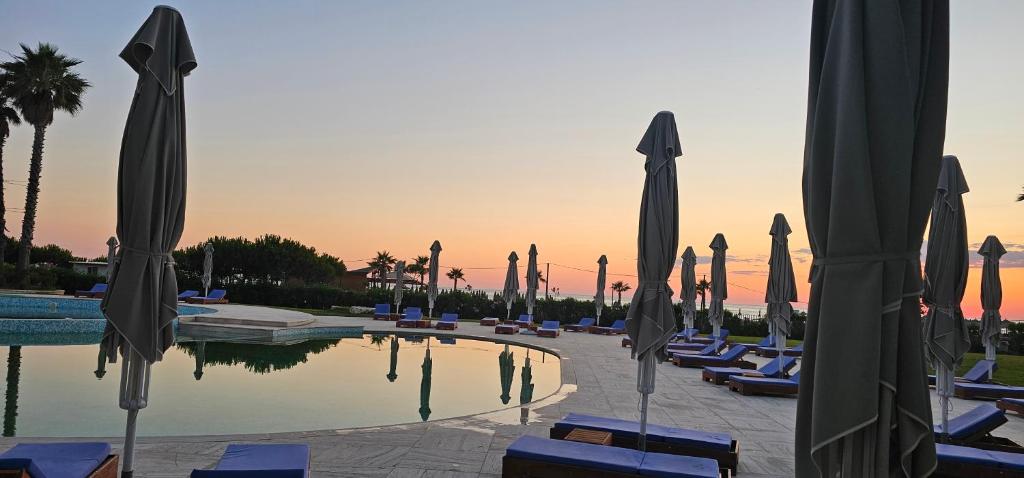 a pool with lounge chairs and umbrellas in a resort at Rrode Apartment Tale Beach in (( Shën Ded Gjoni ))