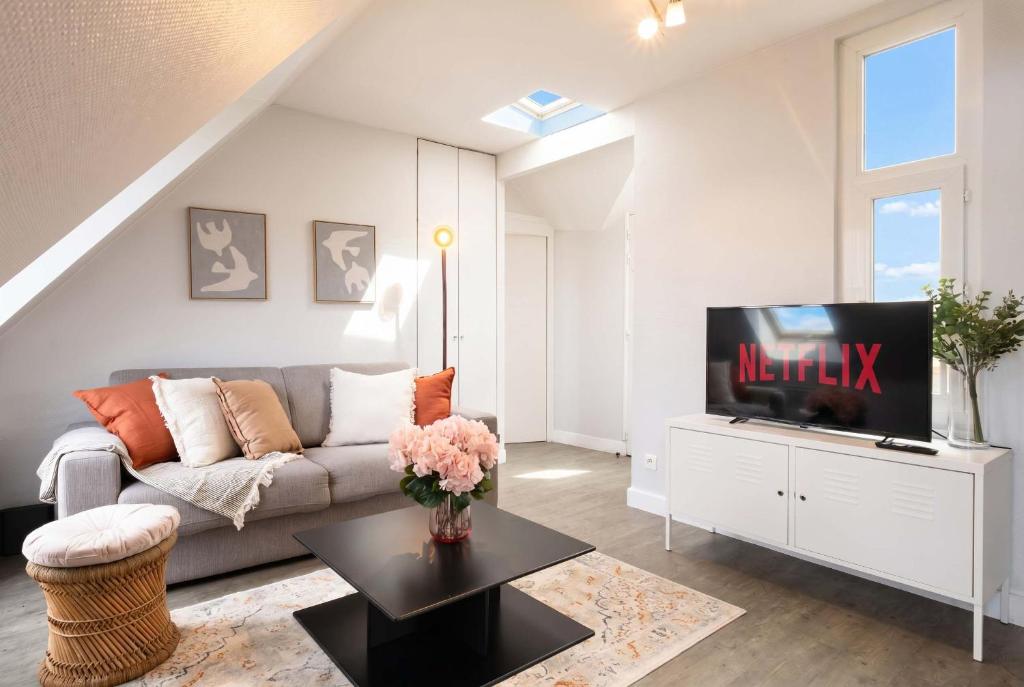 a living room with a couch and a tv at Sebastopol Chic Balcon & Parisian View in Paris