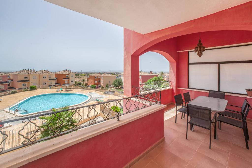 a balcony with a table and chairs and a swimming pool at Sun & Golf Stay in Baños y Mendigo