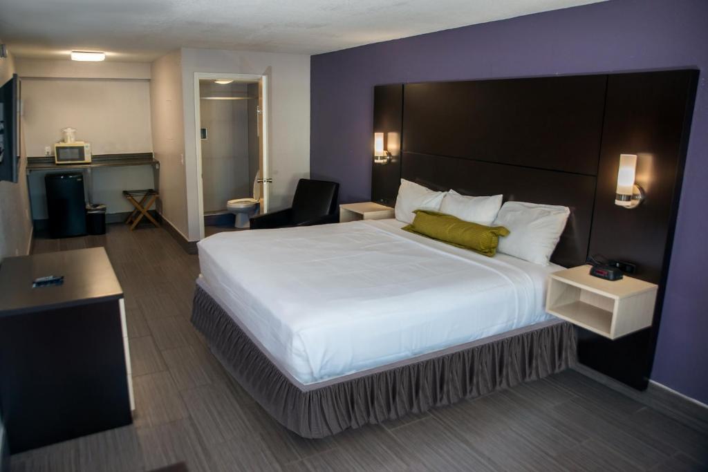 1 dormitorio con cama grande y pared morada en Atlantic Inn, en Melbourne