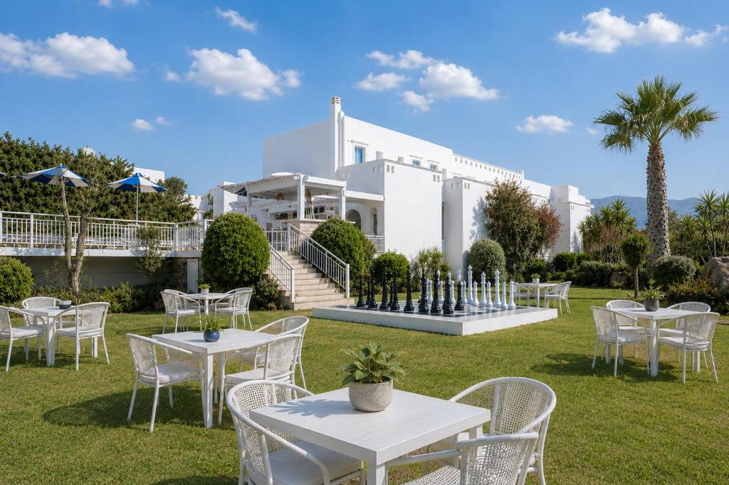 a group of tables and chairs in front of a building at Lagos Mare Hotel in Agios Prokopios