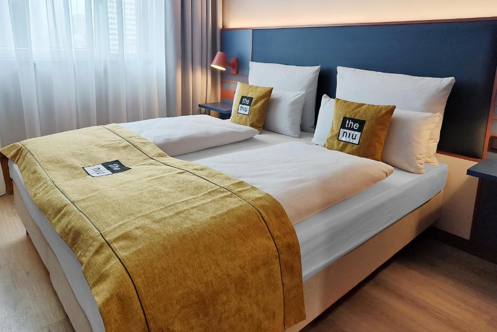 a large bed in a hotel room with pillows at the niu Clink in Hamburg