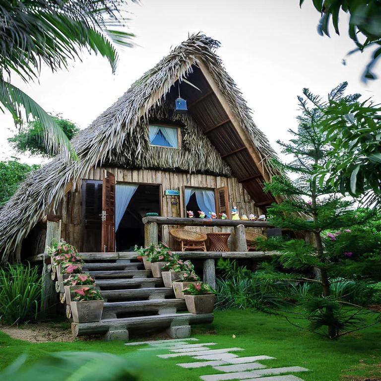 a house with a thatched roof with stairs in front at Veranda Resort Phan Thiết in Tiến Thành