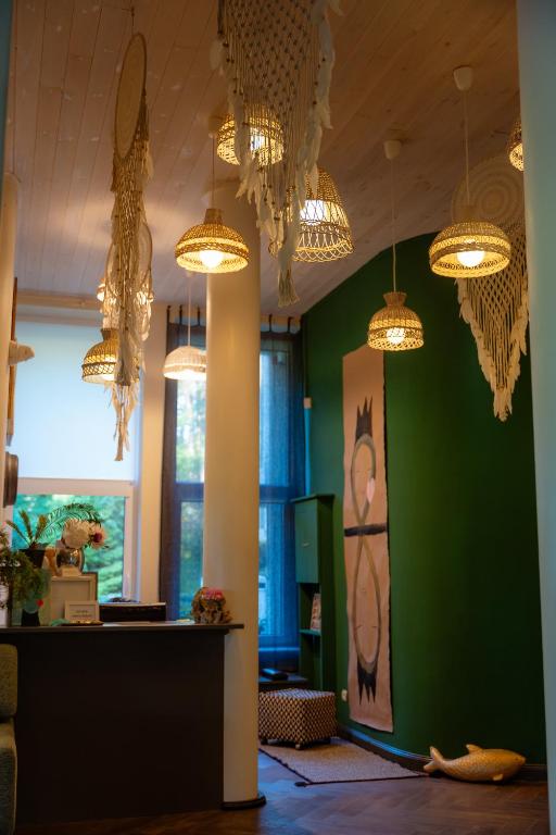 a room with a green wall and chandeliers at Nidos SKALVA in Neringa