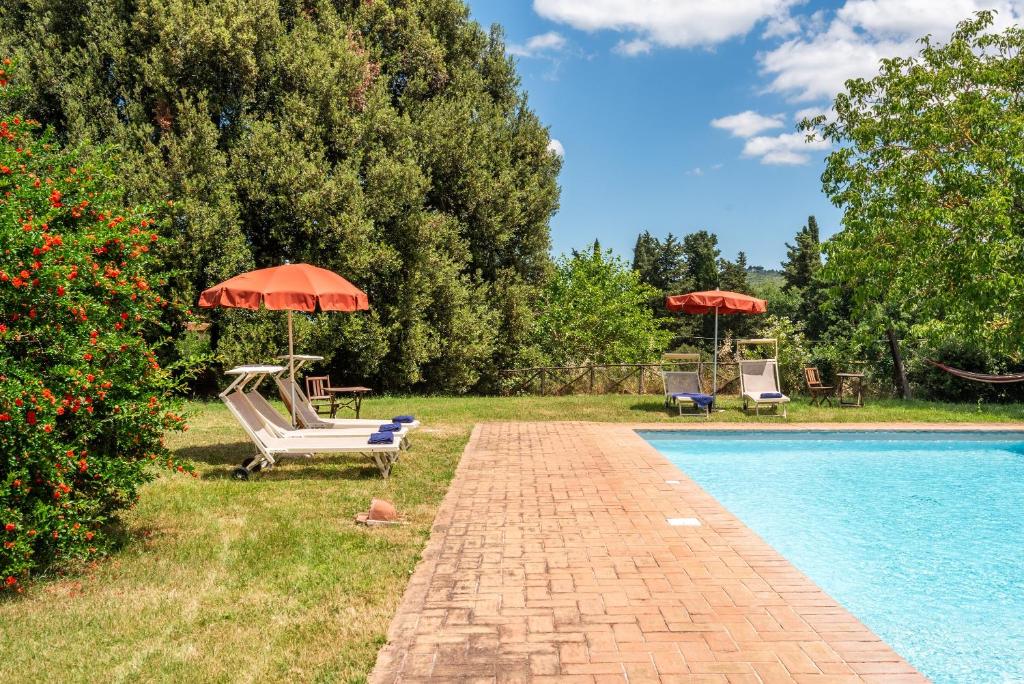 a swimming pool with chairs and umbrellas next to at Tenuta Bichi Borghesi in Monteriggioni