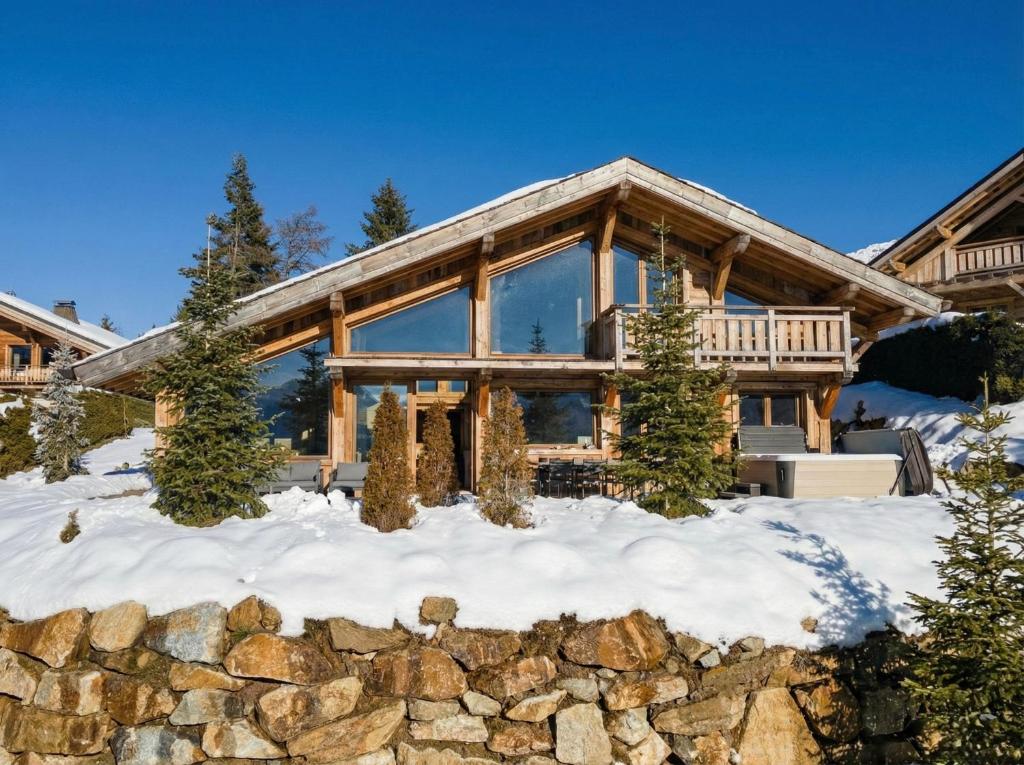 a log home in the snow with a stone wall at Splendide châlet neuf avec jaccuzzi in Bolquere Pyrenees 2000