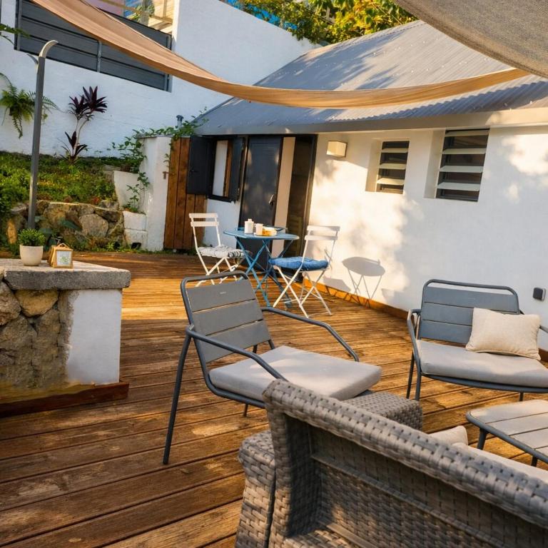 a patio with chairs and a table on a wooden deck at Tite Case Désirée in Petite Île