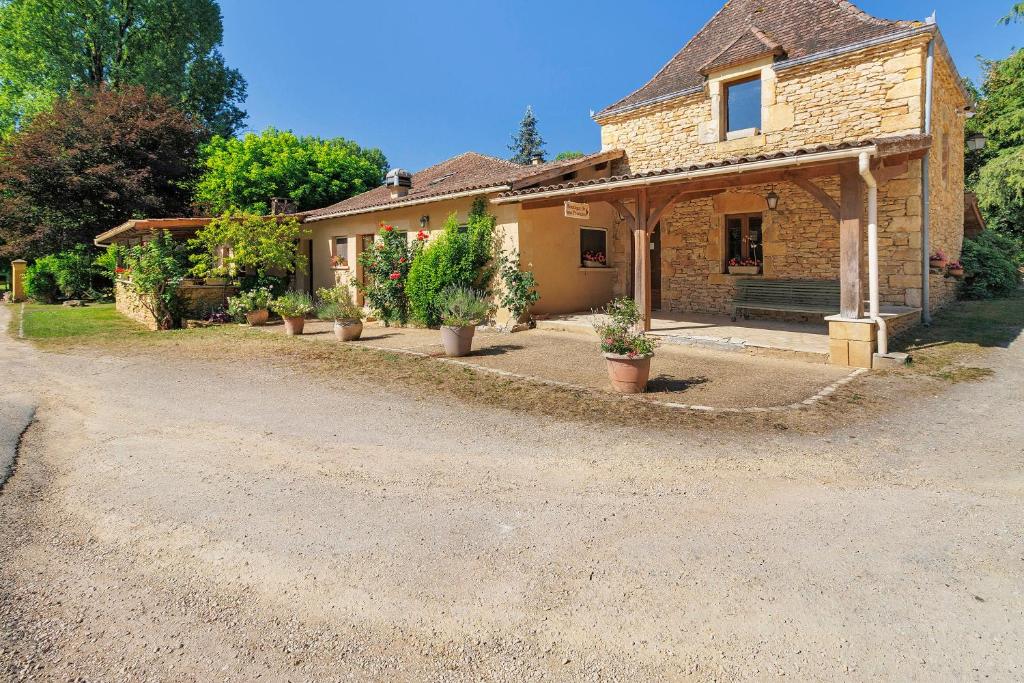 a stone house with potted plants on a gravel driveway at Ferme Auberge Du Roc in Saint-Pompont