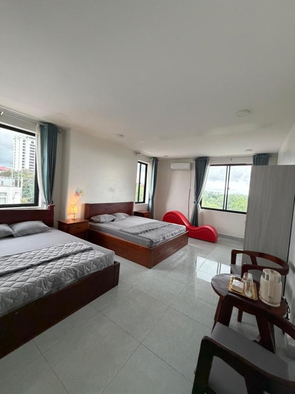 a bedroom with two beds and a chair and windows at J&Q Hotel in Sihanoukville