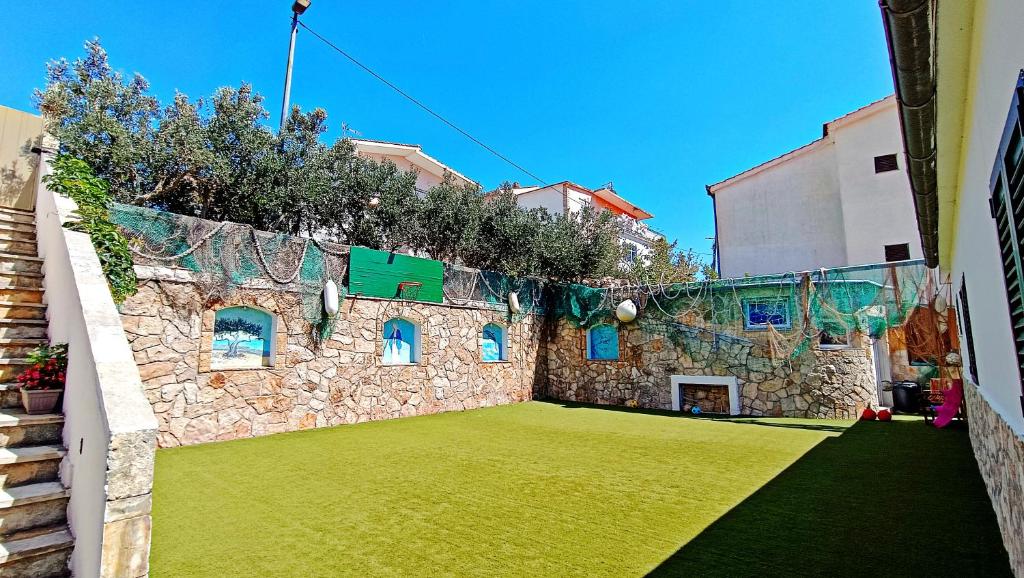 a stone building with a yard with green grass at Apartment Igralište Mirakul in Seget Vranjica