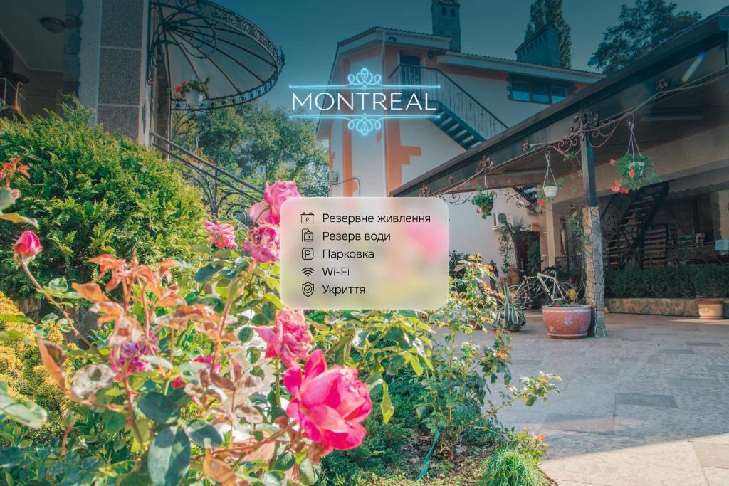 a sign in a garden with flowers in front of a building at Guest House Montreal in Odesa