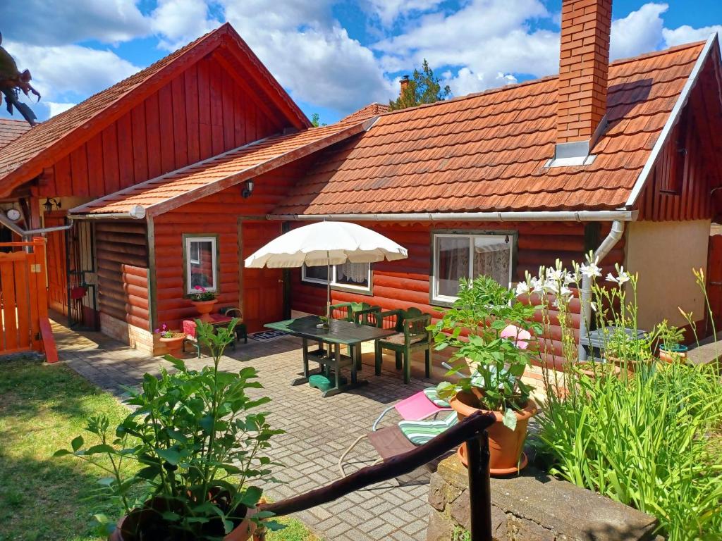 a house with a patio with a table and an umbrella at Fenyő Kuckó in Bodony
