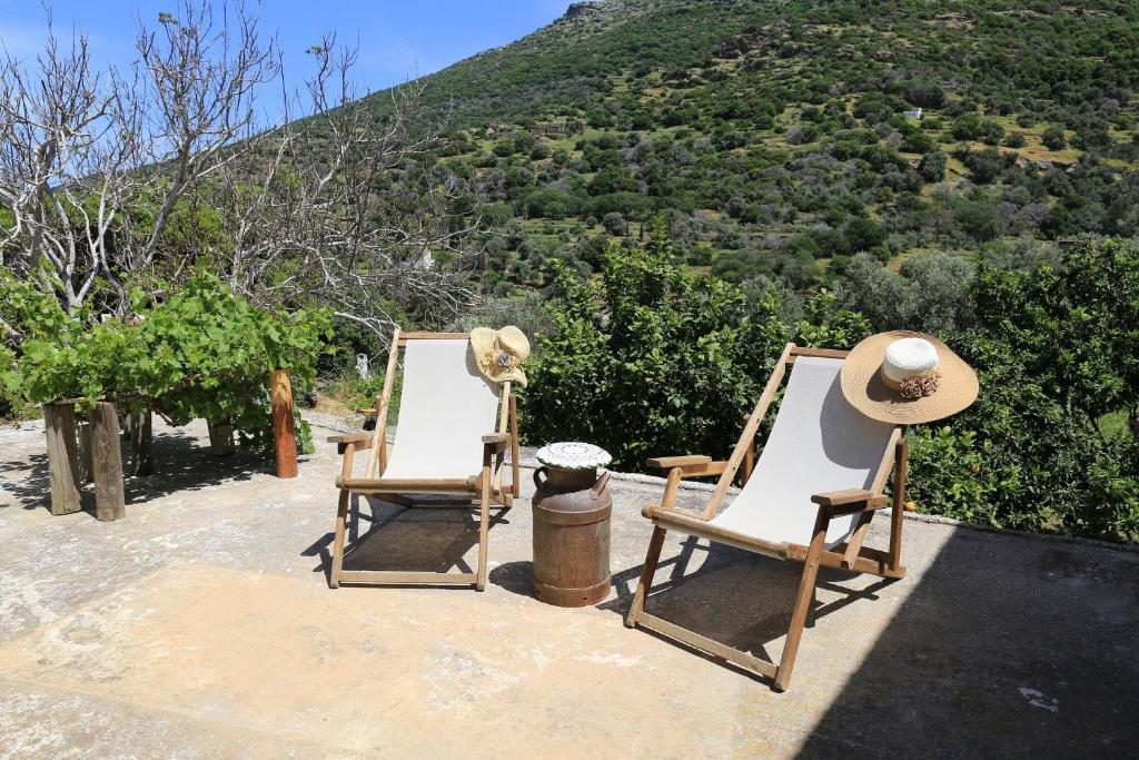 two chairs and a hat sitting on top of a hill at Oak Farm Guest House Junior in Andros