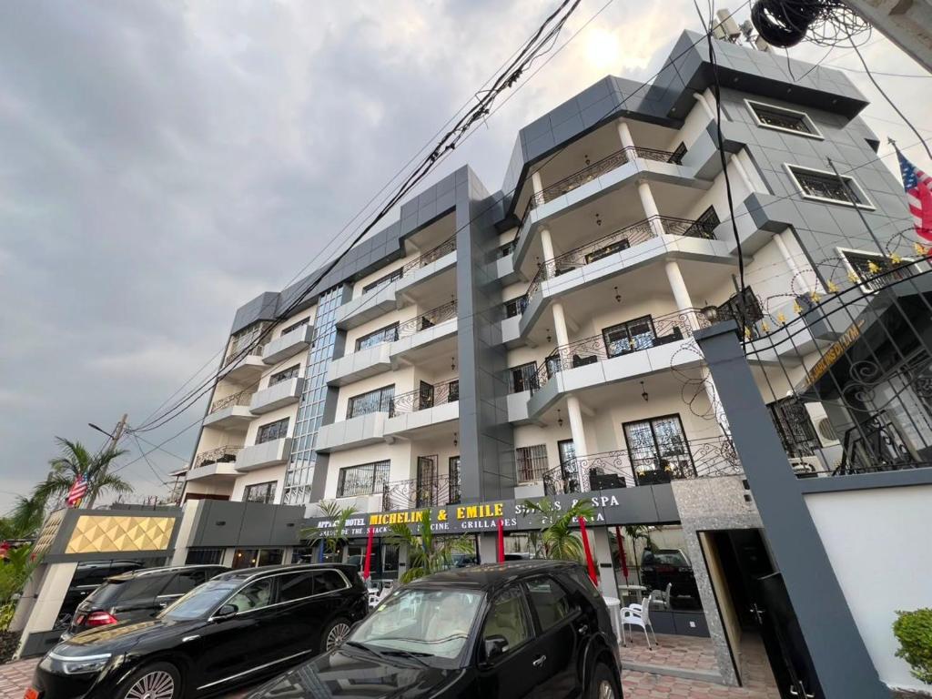 a building with cars parked in front of it at Résidences hôtelières Micheline et Emile BASTOS in Yaoundé