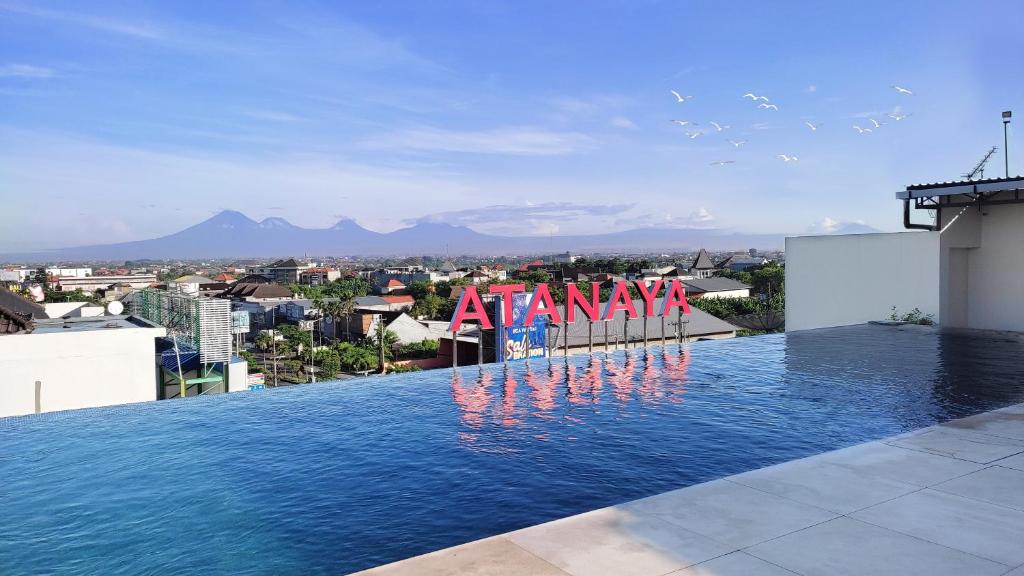 a swimming pool with a sign on top of a building at Atanaya Kuta Bali in Kuta