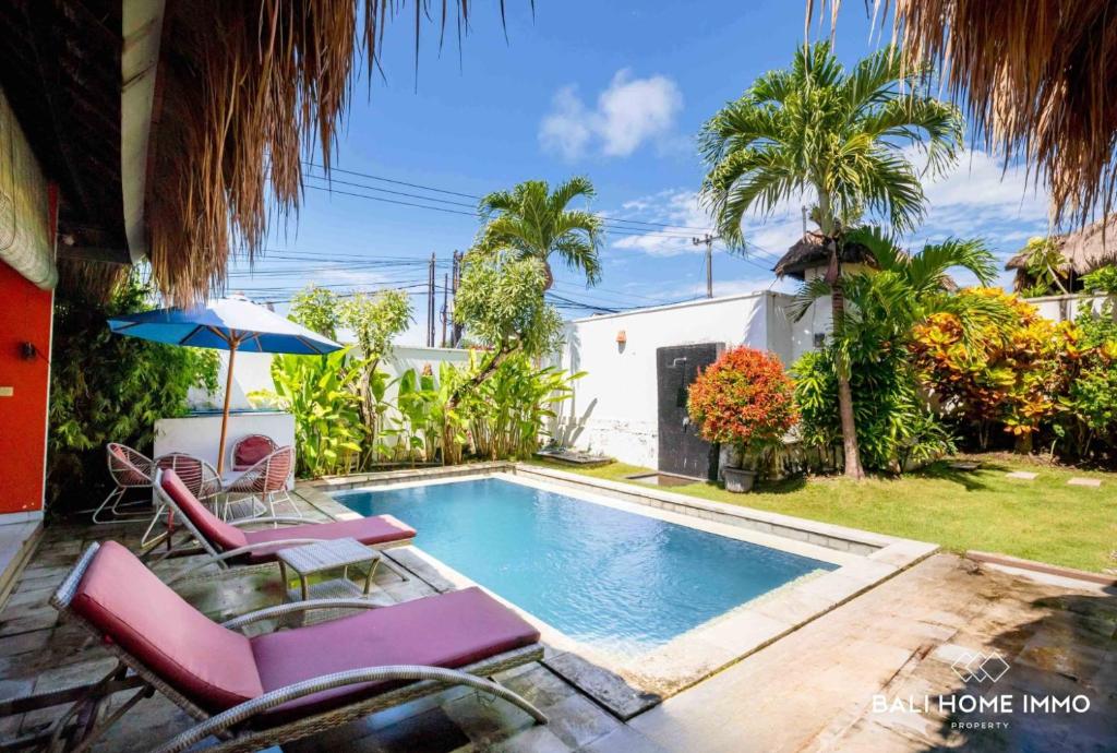 a swimming pool with chairs and an umbrella next to a house at villa TOYA NING in Ungasan
