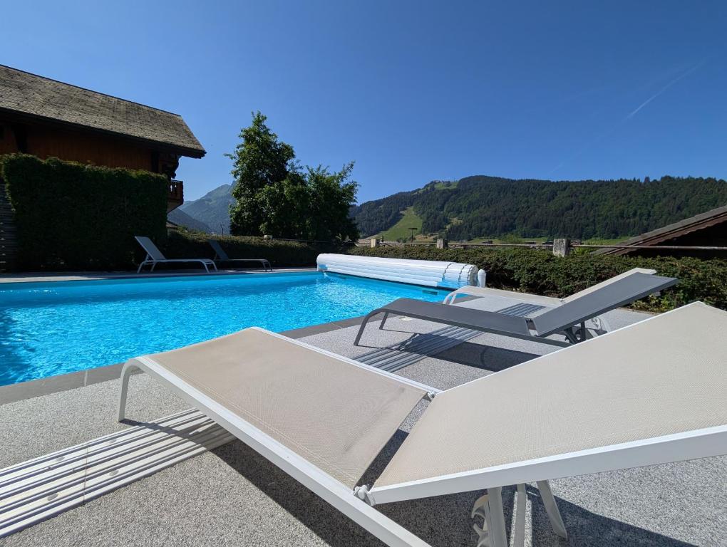a swimming pool with a chaise lounge and a table and a swimming pool at Résidence Julianna , trajets remontées mécaniques , livraison viennoiseries, piscine couverte in Morzine