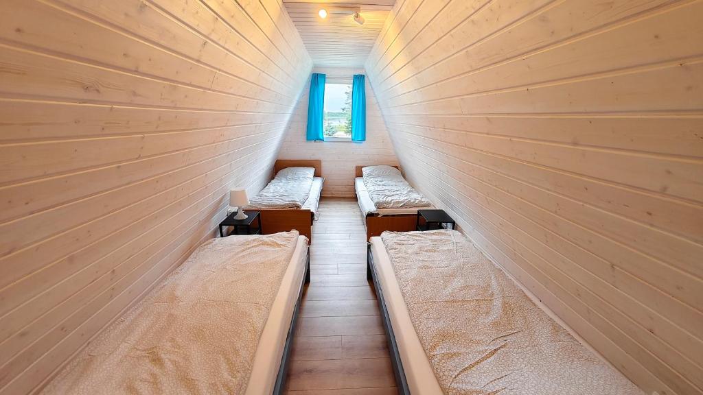 a row of beds in a room with a wall at Nowa Siesta Camp Łeba in Nowęcin