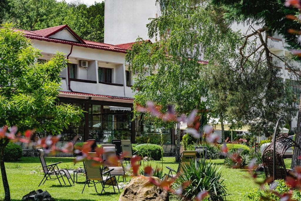 a garden with chairs and tables in front of a building at Hotel Sallaris Monteoru in Sărata-Monteoru