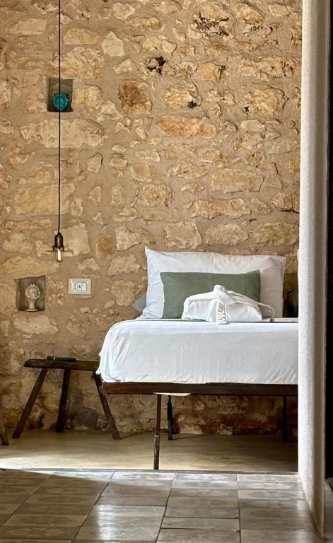 a bed in a room with a stone wall at Casa Farfaglia in Noto