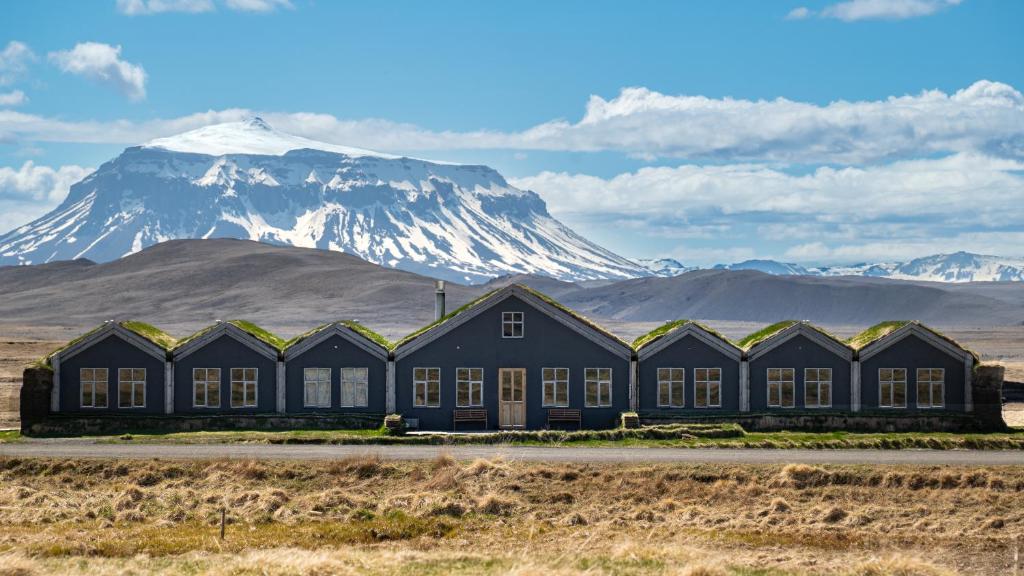 a building with a snow covered mountain in the background at Fjalladýrð Hotel in Modrudalur