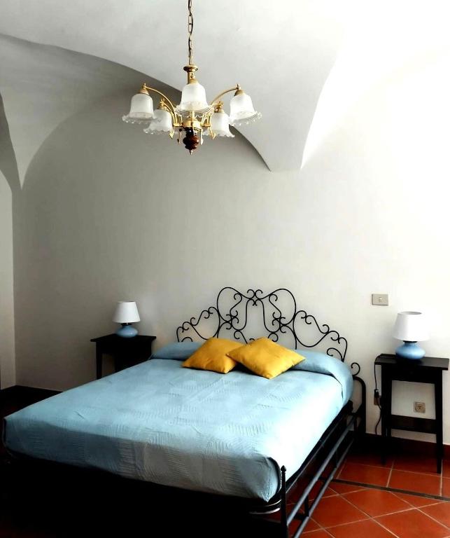 a bedroom with a blue bed with a chandelier at La Piazzetta Alloggio Turistico in Canino