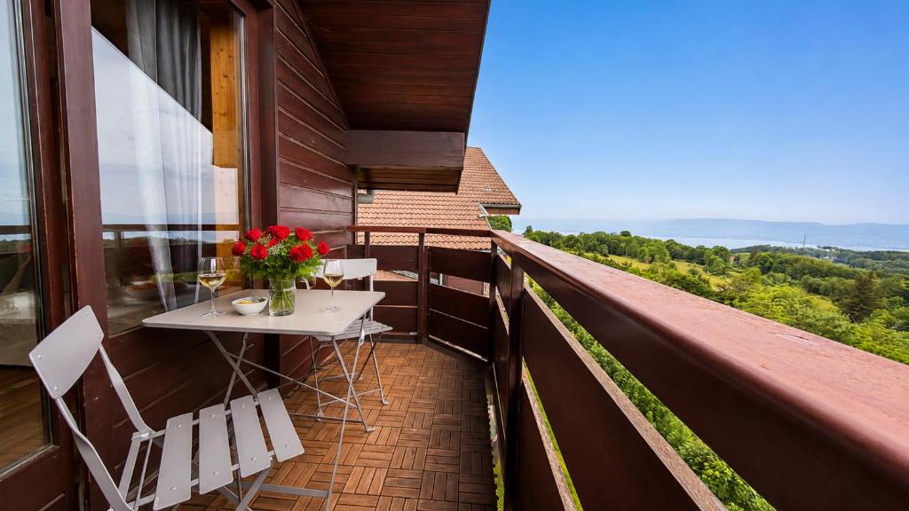 a balcony with a table and chairs on a roof at Vue Lac Léman & Télécabine à 1 minute in Thollon