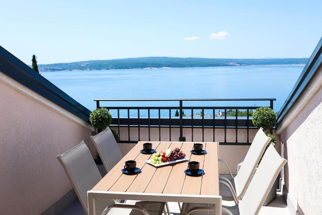 a table on a balcony with a view of the water at Apartments Victoria in Dramalj