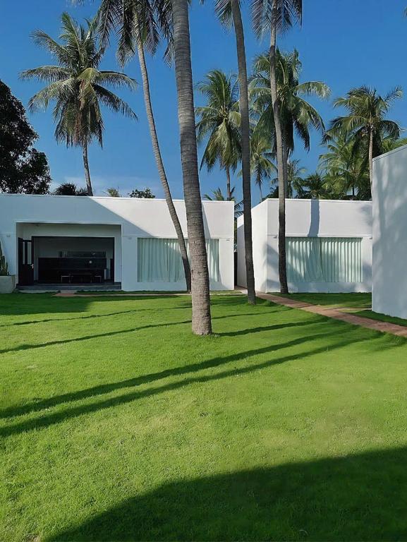 a building with palm trees in front of a yard at 3B MAISON Homestay & Villa in Mui Ne