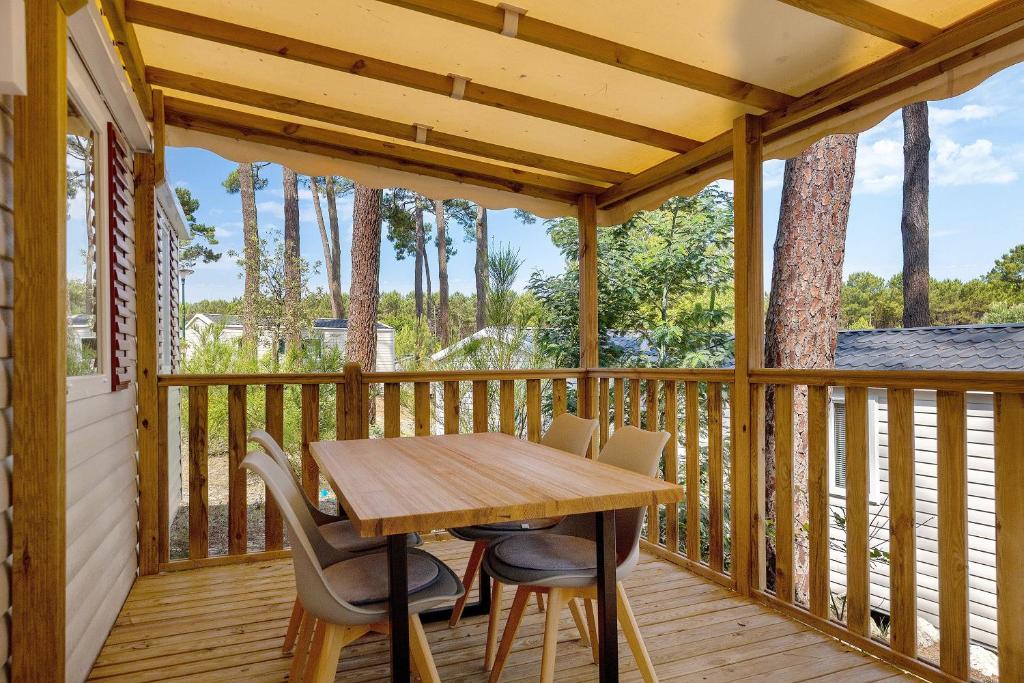 a wooden deck with a wooden table and chairs at Bungalow Cap Ferret Les Lodges 3 in Lège-Cap-Ferret