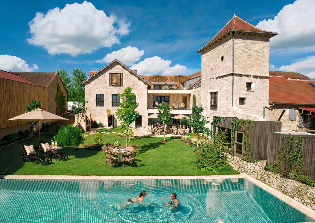 two people swimming in a pool in front of a house at Chez Gratien Hôtel Bistro Spa in Villeneuve-dʼAveyron