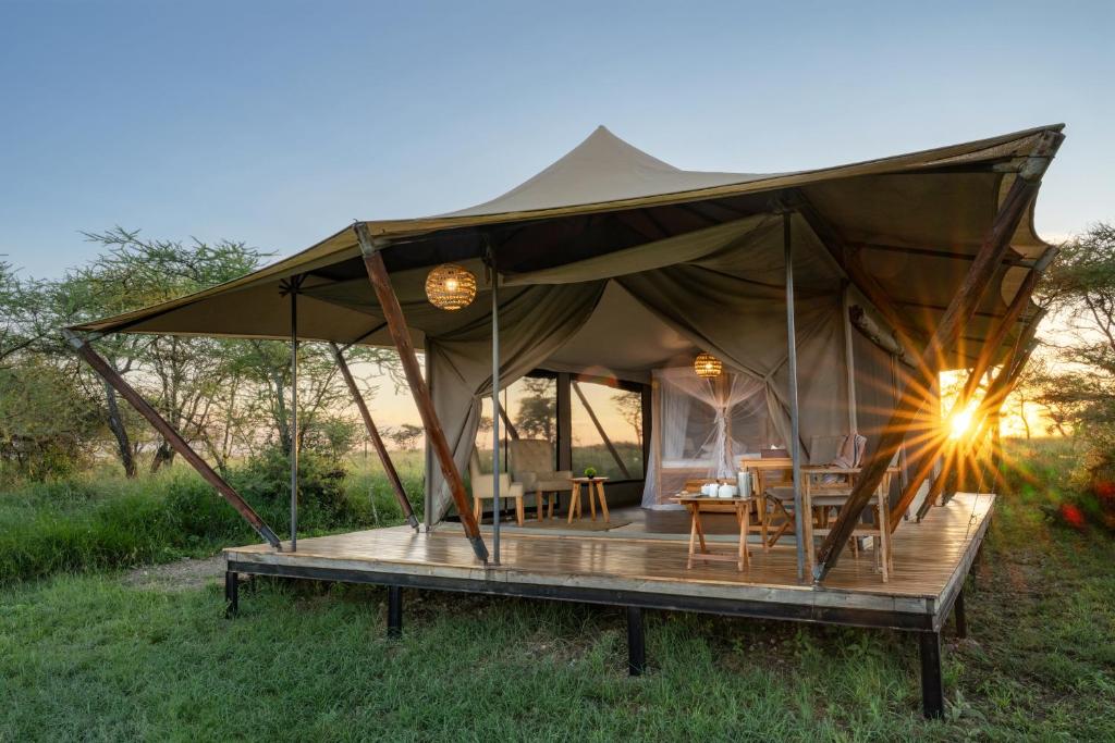 a tent with a table and chairs in a field at Manya Luxury Camp in Serengeti