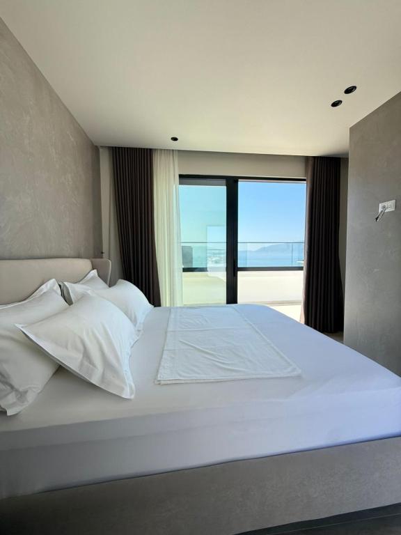 a bedroom with a white bed with a large window at ReiVal Hotel Marina Vlore in Vlorë