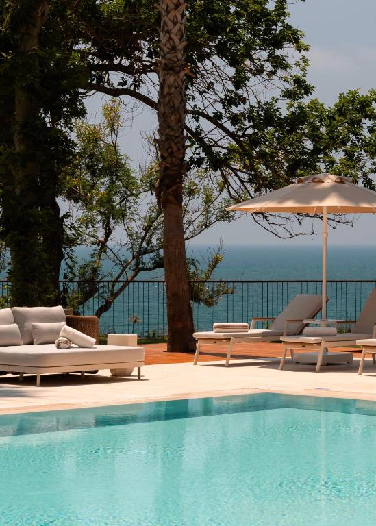 a swimming pool with lounge chairs and an umbrella at Keyla Hotel & Beach - Adult Only in Antalya