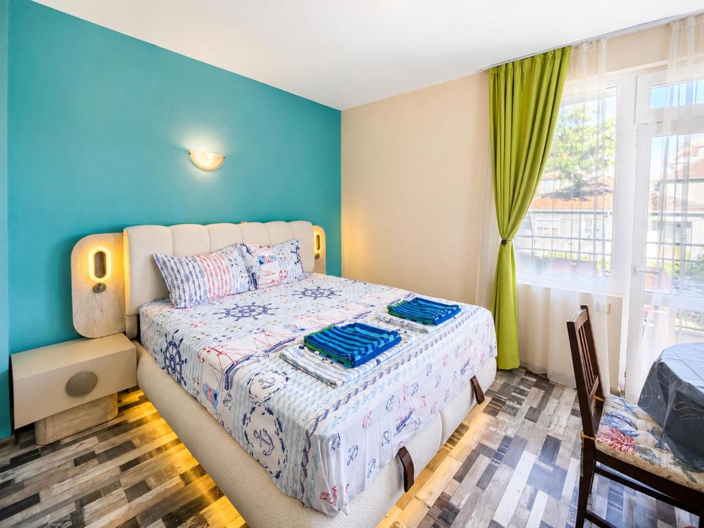 a bedroom with a bed and a blue wall at Kazlarov Guest House in Kiten