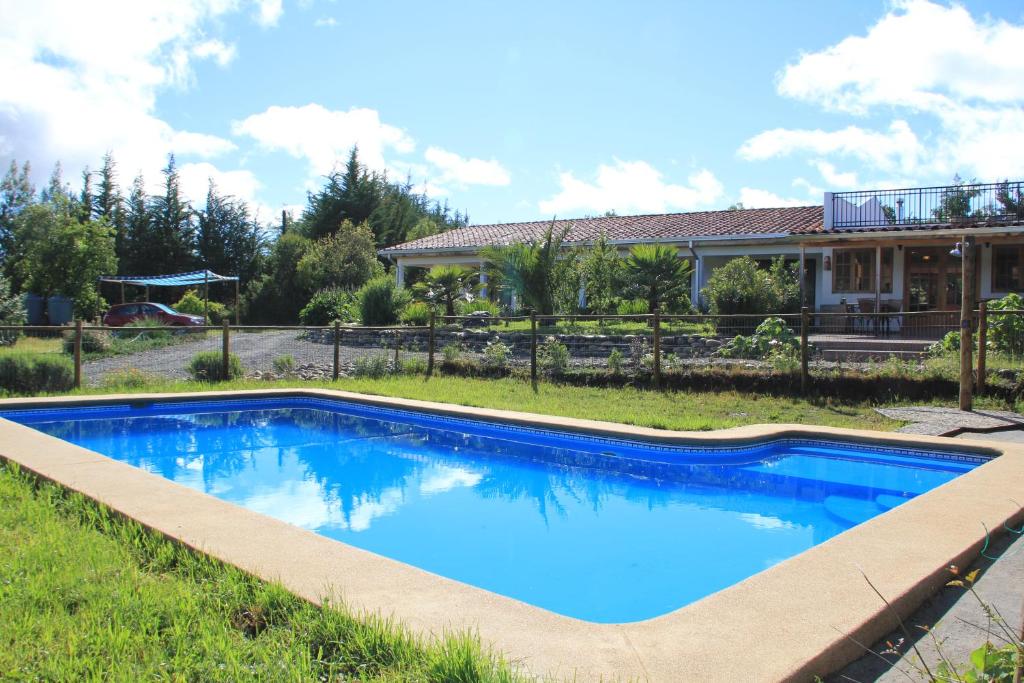 a blue swimming pool in front of a house at La Maravilla Lodge in Vilches