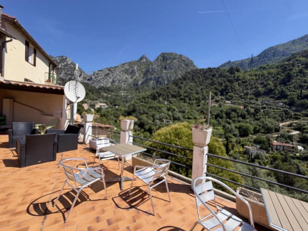 a patio with tables and chairs on a balcony with mountains at HÔTEL Relais de Monti in Menton