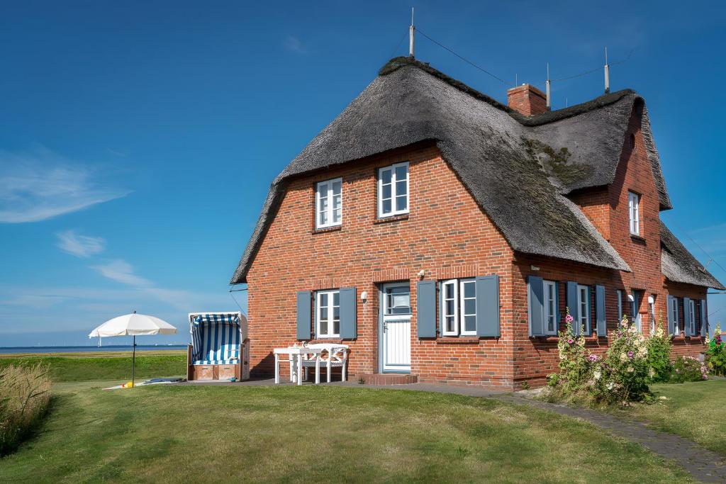 a large red brick house with a thatched roof at Haus Nordmarsch in Langeneß