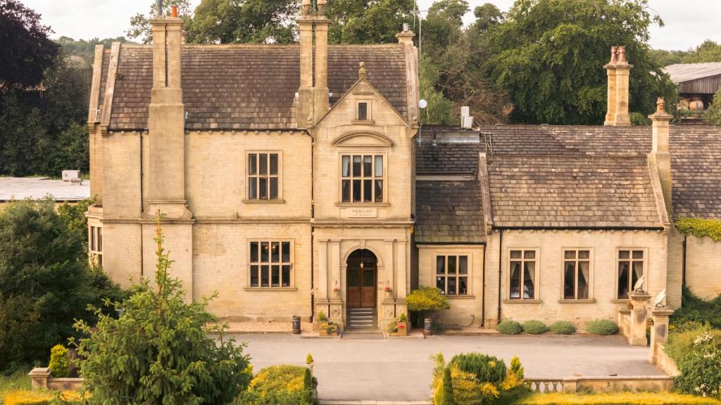 an old stone house with a large front yard at Bagden Hall Hotel in Scissett
