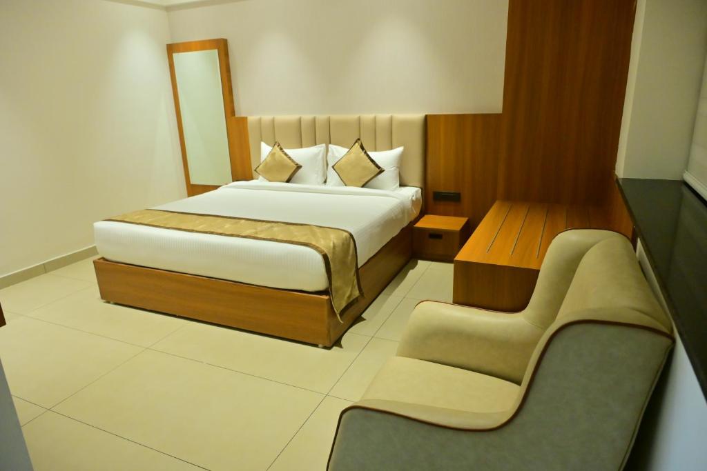 a hotel room with a bed and a chair at BHAVANIS Vista By ICON in Hosūr