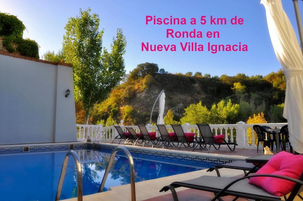a hotel with a swimming pool with chairs and a view at Apartamentos Baiti Ronda in Ronda