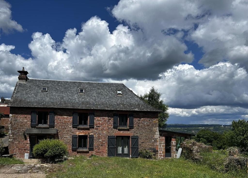 an old brick house on top of a hill at La jolie maison en grès rouge in Lagleygeolle