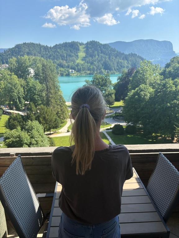 a woman sitting on a bench looking out at a lake at Lake and Castle view apartment in Bled