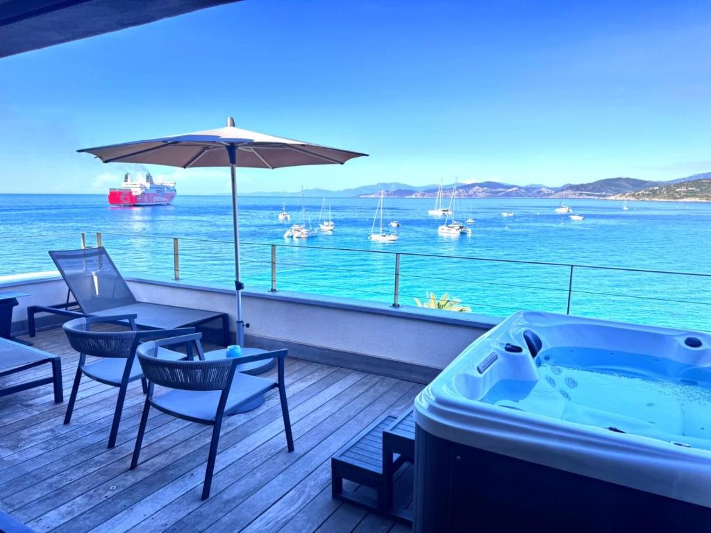 a hot tub sitting on a deck next to the ocean at L'Escale Côté Sud in LʼÎle-Rousse