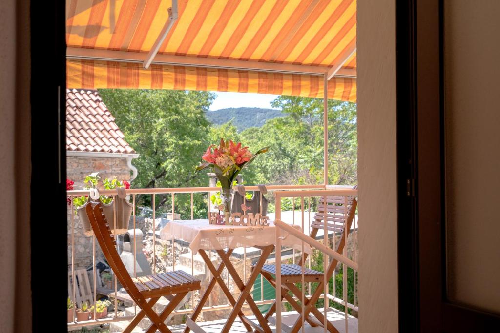 a table with chairs and a vase of flowers on a balcony at Guesthouse Wish in Stari Grad