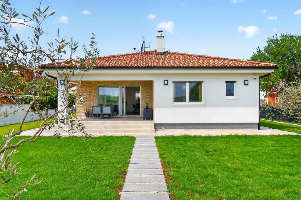 a small white house with a green lawn at Villa Tea by Rent Istria in Umag